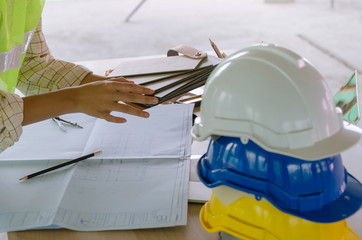 Wall Mural - professional architect, engineer or interior design hands working with safety helmet on workplace desk in office center at construction site, contractor, interior, construction and engineering concept