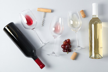 Wall Mural - Flat lay. Grapes, corkscrew, bottles and glasses with wine on grey background
