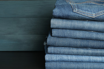 Wall Mural - Stack of jeans pants on black table, space for text