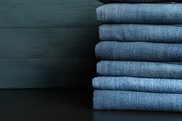 Canvas Print - Stack of jeans pants on black table, space for text