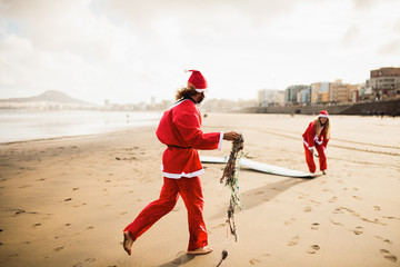 two surfers dressed as Santa Claus on the beach