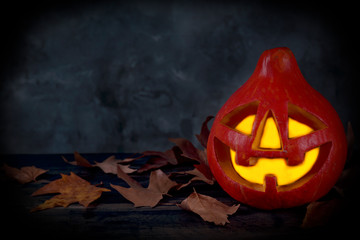 Orange pumpkin carved into creepy and funny Jack o Lantern w/ glowing eyes on dark background. All hallows night. Copy space, close up, top view. Halloween party decoration. Trick or treat concept.