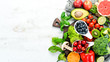 Fresh fruits and vegetables on a white wooden background. Top view. Free space for your text.