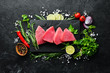 Raw tuna fillet. Seafood on a black stone background. Top view. Free copy space.