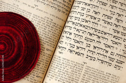 Fotografía An opened old Jewish Bible and red knitted jewish bale