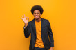 © Asier - Young business african american man over an orange wall cheerful and confident doing ok gesture