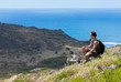 © kieferpix - Male hiker sitting on mountain ridge enjoying the sea side cliff views.