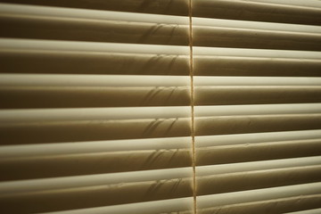 closed horizontal blinds, sunlight through them, macro photo