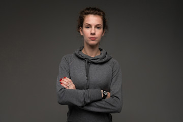 Portrait of young woman in grey hoodie against gloomy background isolated