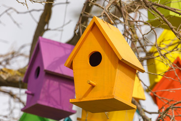 Closeup of light orange birdhouse on tree