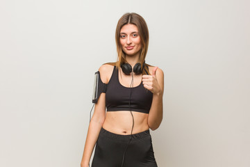 Wall Mural - Young fitness russian woman smiling and raising thumb up