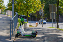 Group Of E-scooters From Startup Company With Idea Of Eco Friendly Mobility For Urban Lifestyle By Sharing Electric Scooter, Park On Shady Sidewalk In Cologne, Germany.