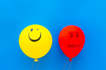 Wall Mural - Treat depression concept. Balloons with frustrated and smiling faces on blue background top view