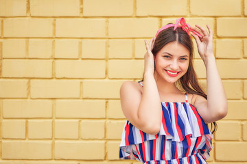 close-up young woman with a pink bow emotionally fun posing on a background of a yellow brick wall. copy space