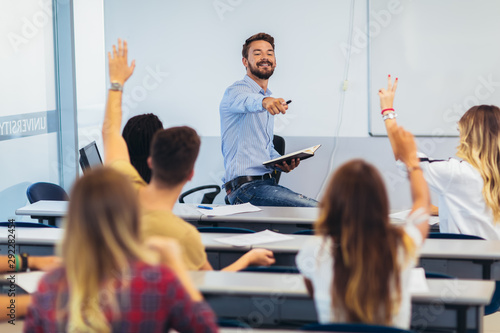 Fotografía Group of students raising hands in class on lecture