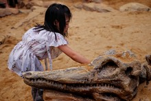 A Pretty Asian Girl Playing In A Sandbox With A Modeled Dinosaur Fossil