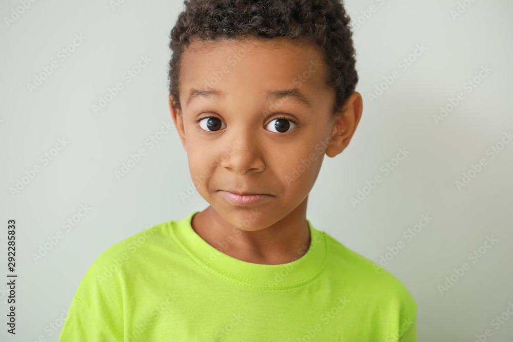Confused African-American boy on light background