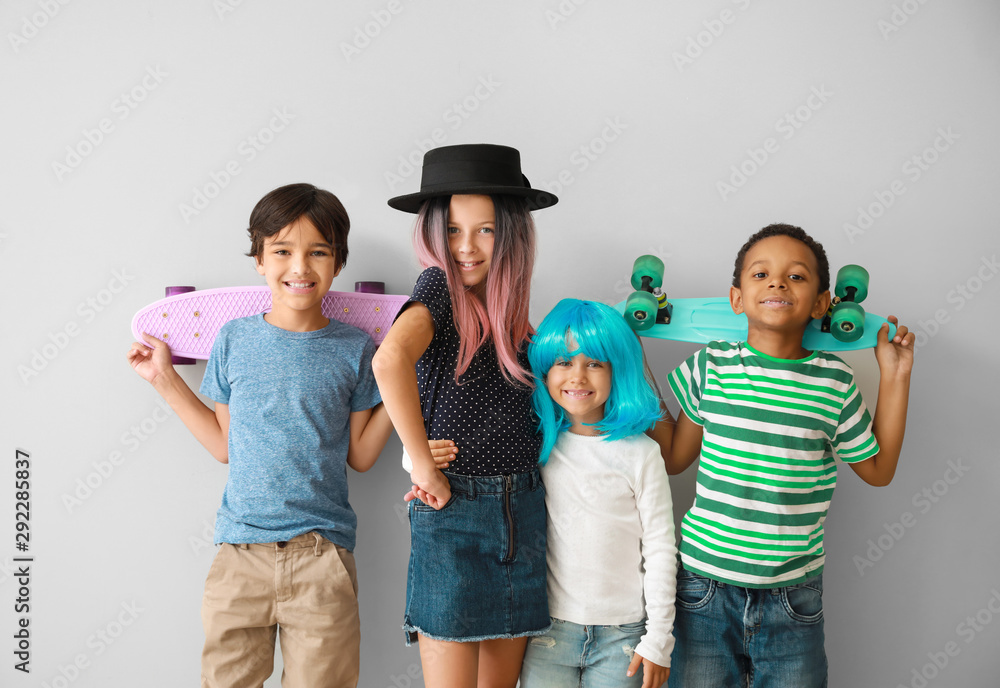Stylish little children with skateboards on light background