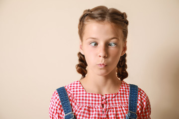 Grimacing little girl on light background