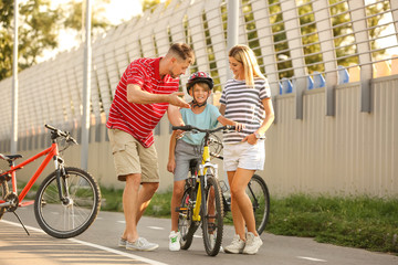 Poster - Parents teaching their son to ride bicycle outdoors