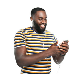 Wall Mural - Happy African-American man listening to music on white background