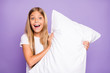 © deagreez - Portrait of funny crazy model kid hold hand pillow want have fun on sleep-over party feel content expression play pillow fights with her friends wear white t-shirt isolated over purple color