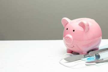  How to save on expensive surgery. Scalpel and syringe near the piggy bank