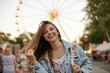 © timtimphoto - Charming pretty young lady with long brown hair posing over ferris wheel in casual clothes, waving her hair and smiling cheerfully to camera, positive emotions concept