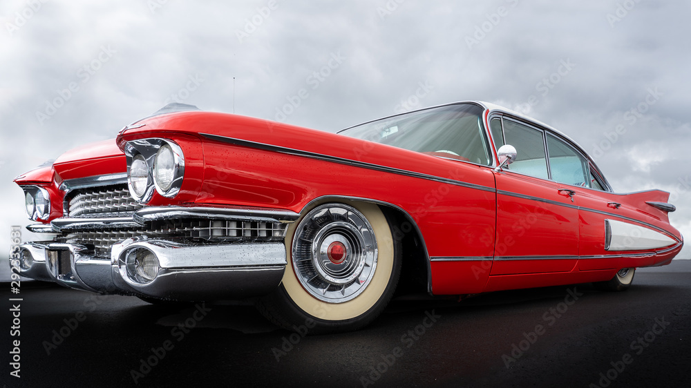 Side view of a classic american car from the fifties. Low angle view showing red paint and chrome fender and grill. - obrazy, fototapety, plakaty 