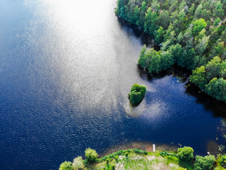 Aerial view of blue lake and green forest on a sunny summer day in Finland. Drone photography