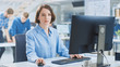 © Gorodenkoff - In the Industrial Engineering Facility: Portrait of the Smart and Beautiful Female Engineer Working on Desktop Computer. In the Background Specialists and Technicians Working with Drafts and Drawings