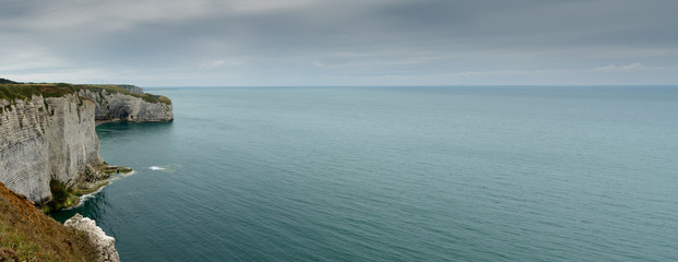 panorama view of ocean and coast with green fields and jagged cliffs