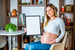 Young beautiful pregnant girl holding white empty board in her home during daytime