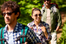 Travel, Tourism, Hike And People Concept - Group Of Friends Walking With Backpacks In Forest