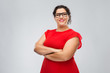 © Syda Productions - vision, education and eyesight concept - happy woman in red dress and glasses with crossed arms over grey background