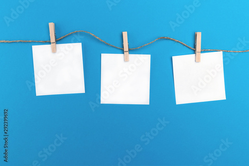 Cuadros en Lienzo Three empty little sheets of paper hold by wooden clothespins on a string