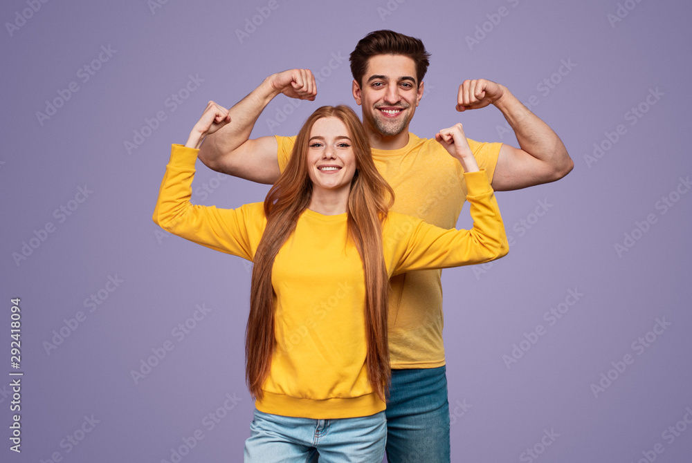 Cheerful young couple flexing muscles - obrazy, fototapety, plakaty 