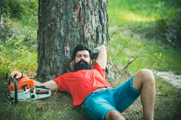 Wall Mural - Lumberjack worker sitting in the forest. Resting after hard work.