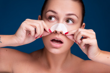 Brunette caucasian woman get rid off black dots on her nose using special patch. Flawless clean skin. Beauty skin care concept