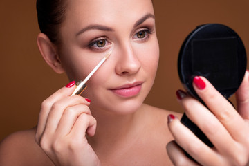 Brunette caucasian woman apply concealer under her eyes. Flawless clean skin. Beauty skin care concept