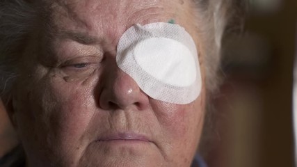 old woman with protective eye patch after cataract surgery.