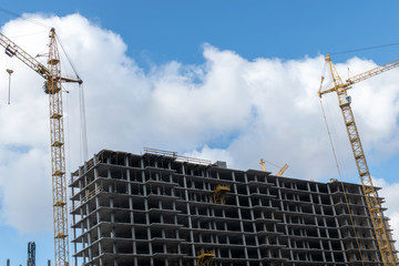 High rise building with cranes under construction. big building construction site against blue sky with white cloud. Industrial background