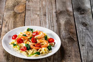 Shrimps with pasta tagliatelle with spinach and tomatoes