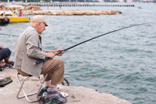Old Man Fishing On A Fishing Rod In The Sea, In The Evening