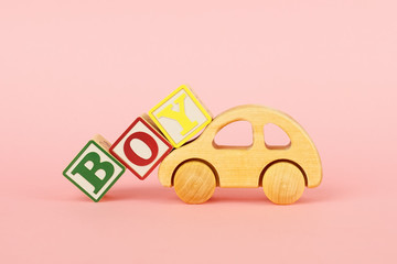 Wall Mural - Colored cubes with letters Boy and car toy on a pink background