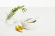 mortar and pestle with herbal mix and and glass with fresh plants on white background