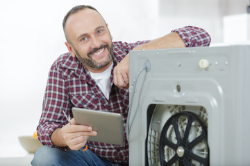 man using tablet pc for fixing a washing machine