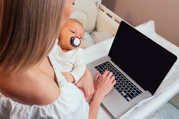 Happy single blonde mother working online and taking care of her baby (surfing question on the internet)