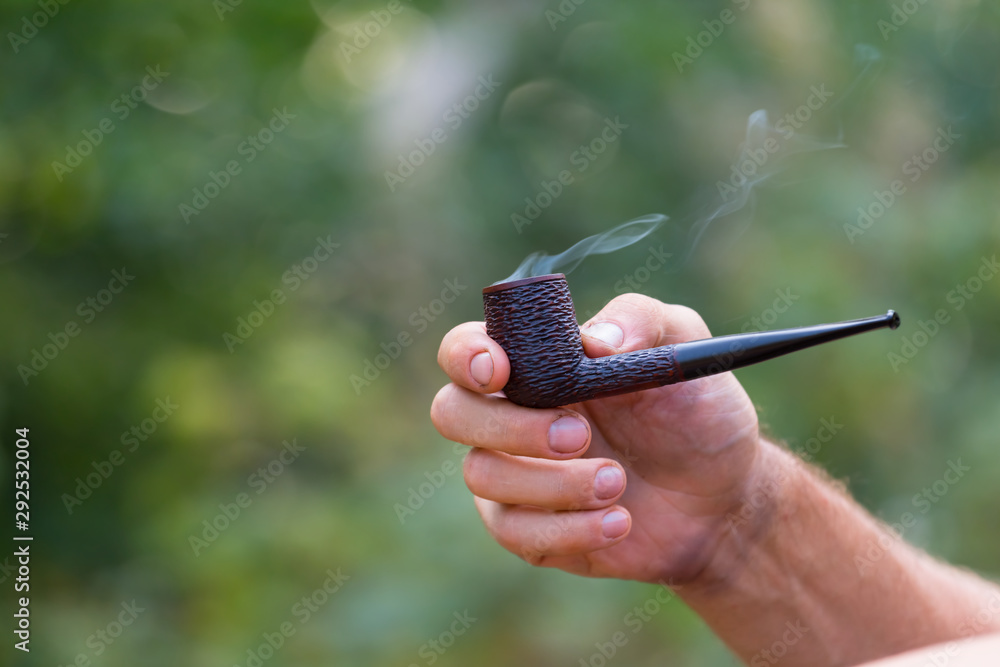 human hold smoking pipe by hand in a coils of smoke Stock Photo