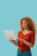 © LIGHTFIELD STUDIOS - beautiful redhead woman using laptop isolated on blue
